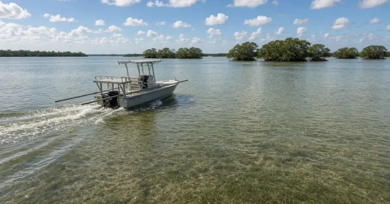 Bay boat running across shallow green water past mangrove islands