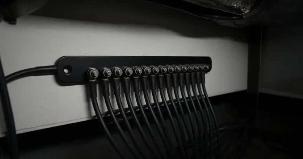 Black negative busbar with a row of return wires landed on its terminals inside a boat