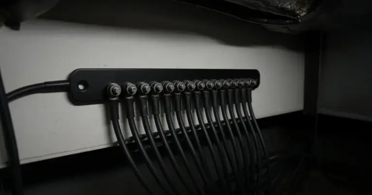 Black negative busbar with a row of return wires landed on its terminals inside a boat